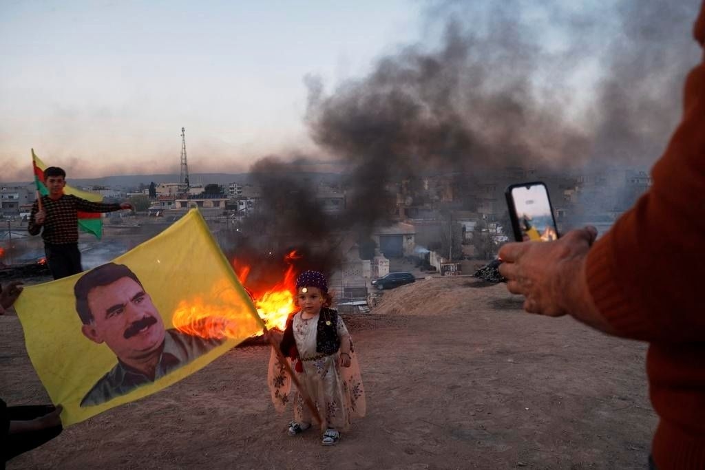 A child holds a flag bearing the image of Kurdish leader Abdullah Ocalan during Nowruz celebrations in Amuda, Hasakah region, Syria.