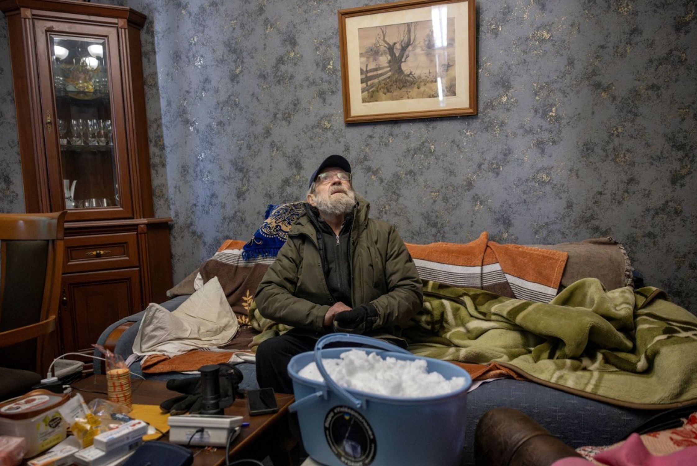 A Kyiv resident with a bucket of snow in his apartment, Jan. 10, 2026